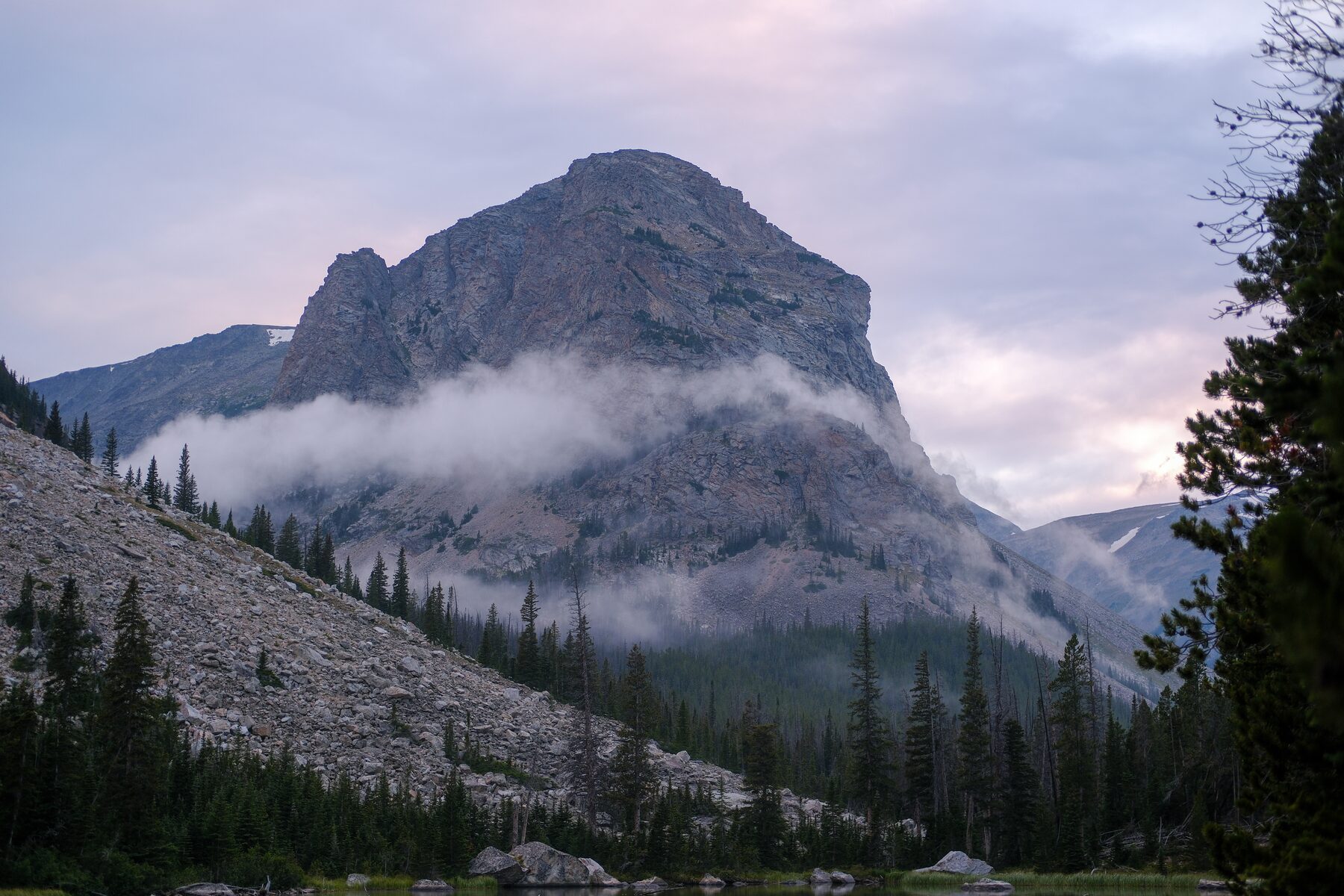 Rocky peak with clouds hanging on its shoulder at dusk