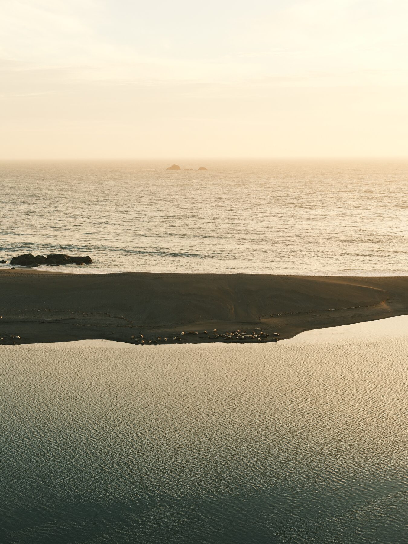 Dark sand spit dividing calm water from the ocean