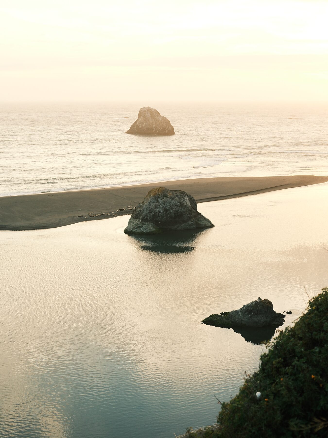 Sea stacks on a glassy tidal flat at sunset